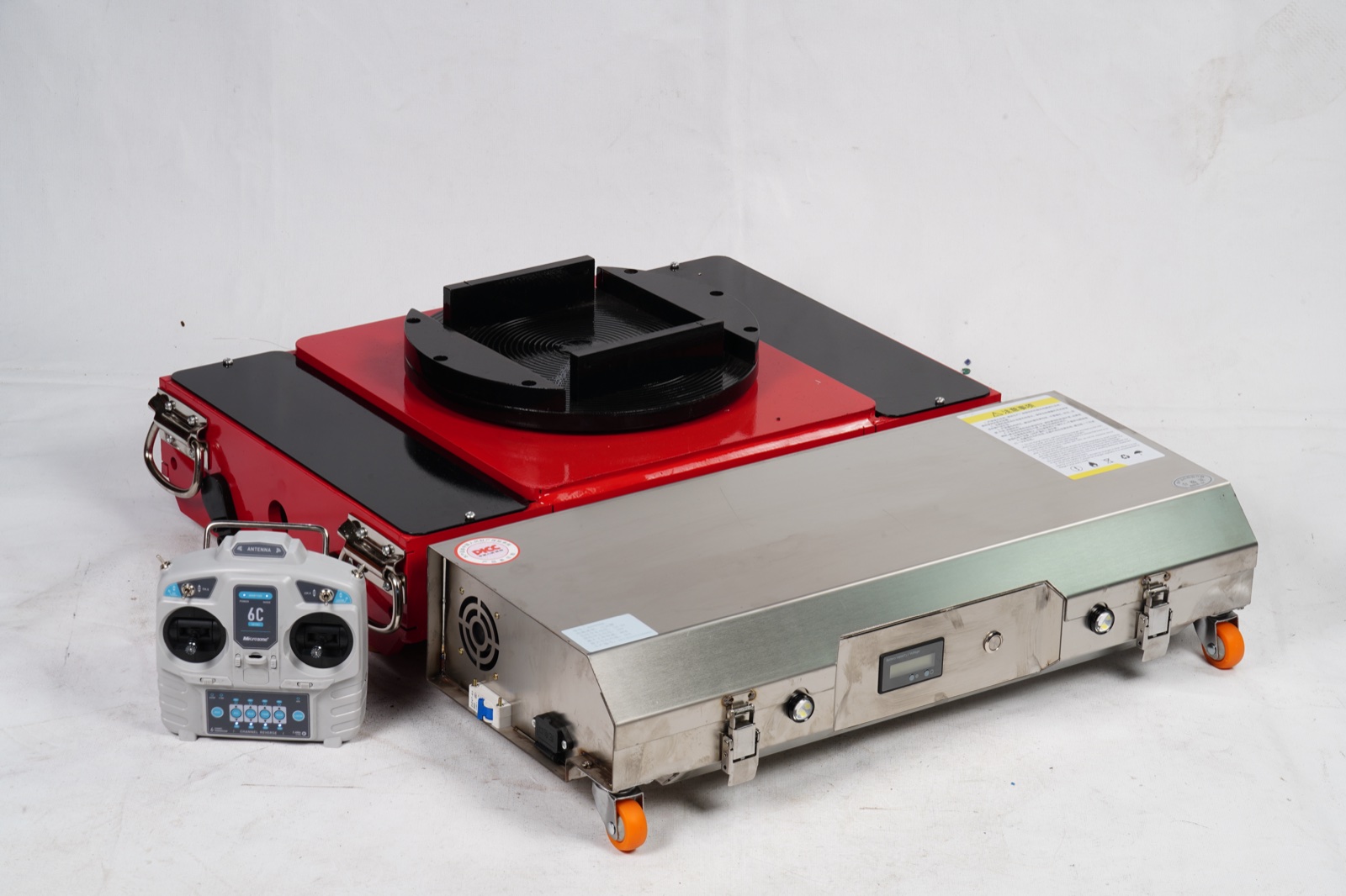 Electric tank carrier top view — red rotating turntable with spiral grooves, stainless steel chassis side, wireless remote controller placed beside